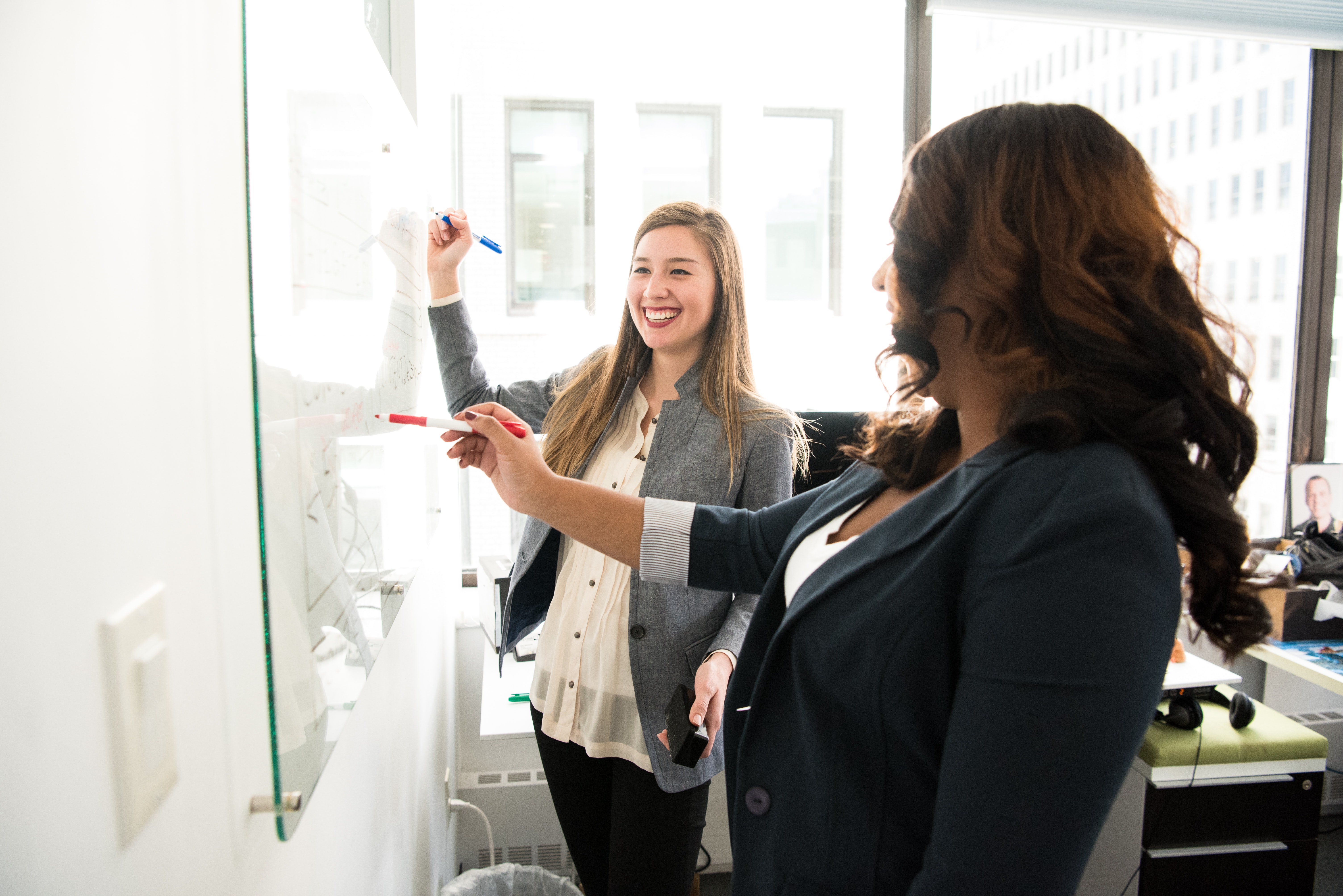 two-women-in-front-of-dry-erase-board